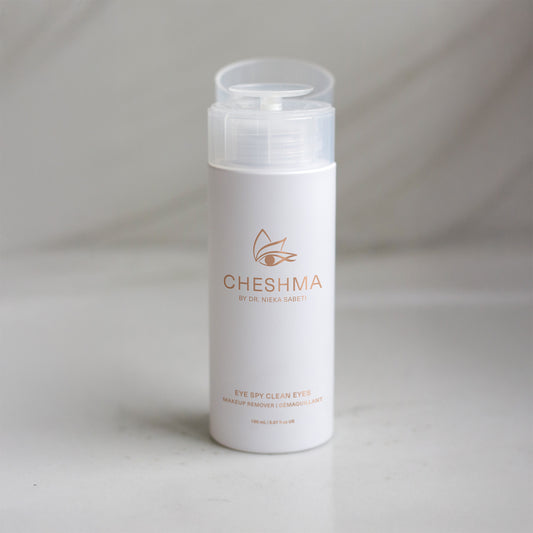 A bottle of Cheshma eye makeup remover with a sleek design, surrounded by clean ingredients, promoting a refreshing enjoyable experience.