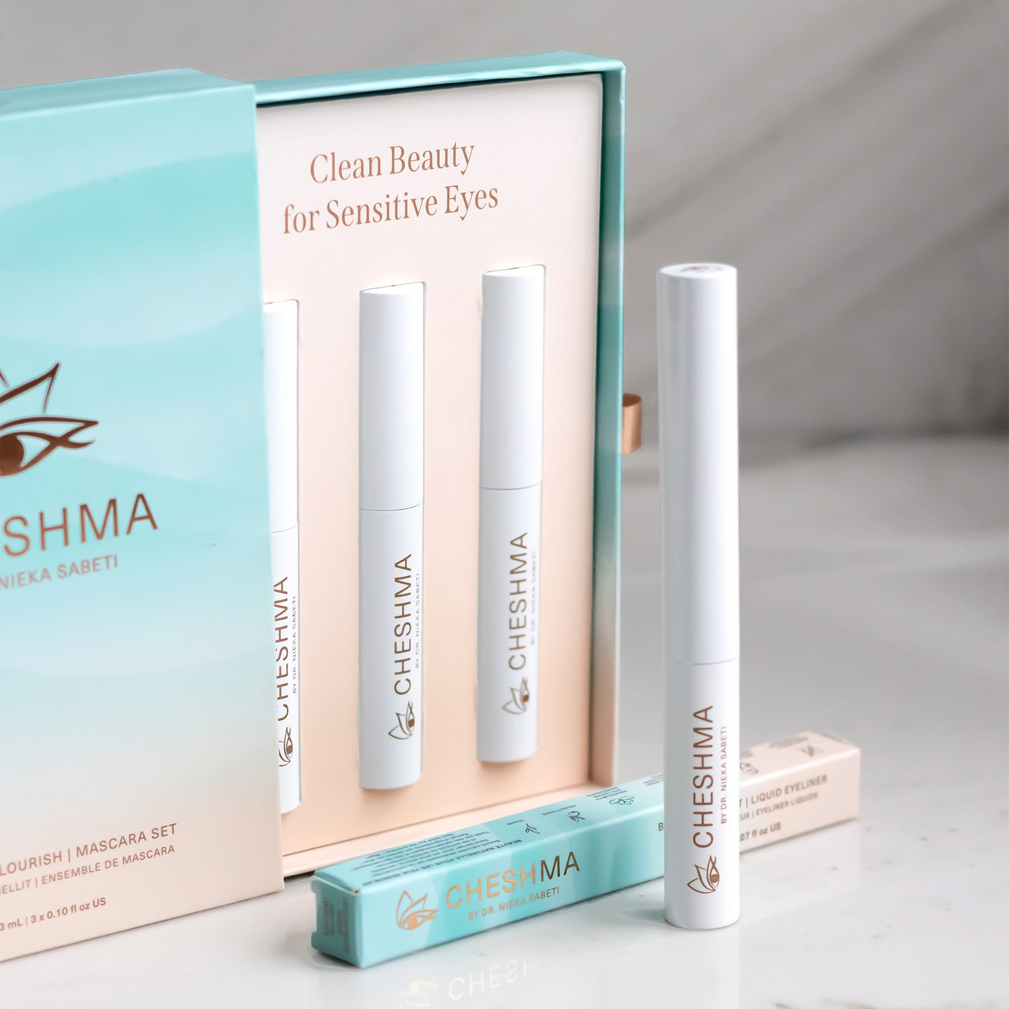 teal blue wave box with sand colour inside with mascara white vials and eyeliner on marble countertop of Cheshma brand