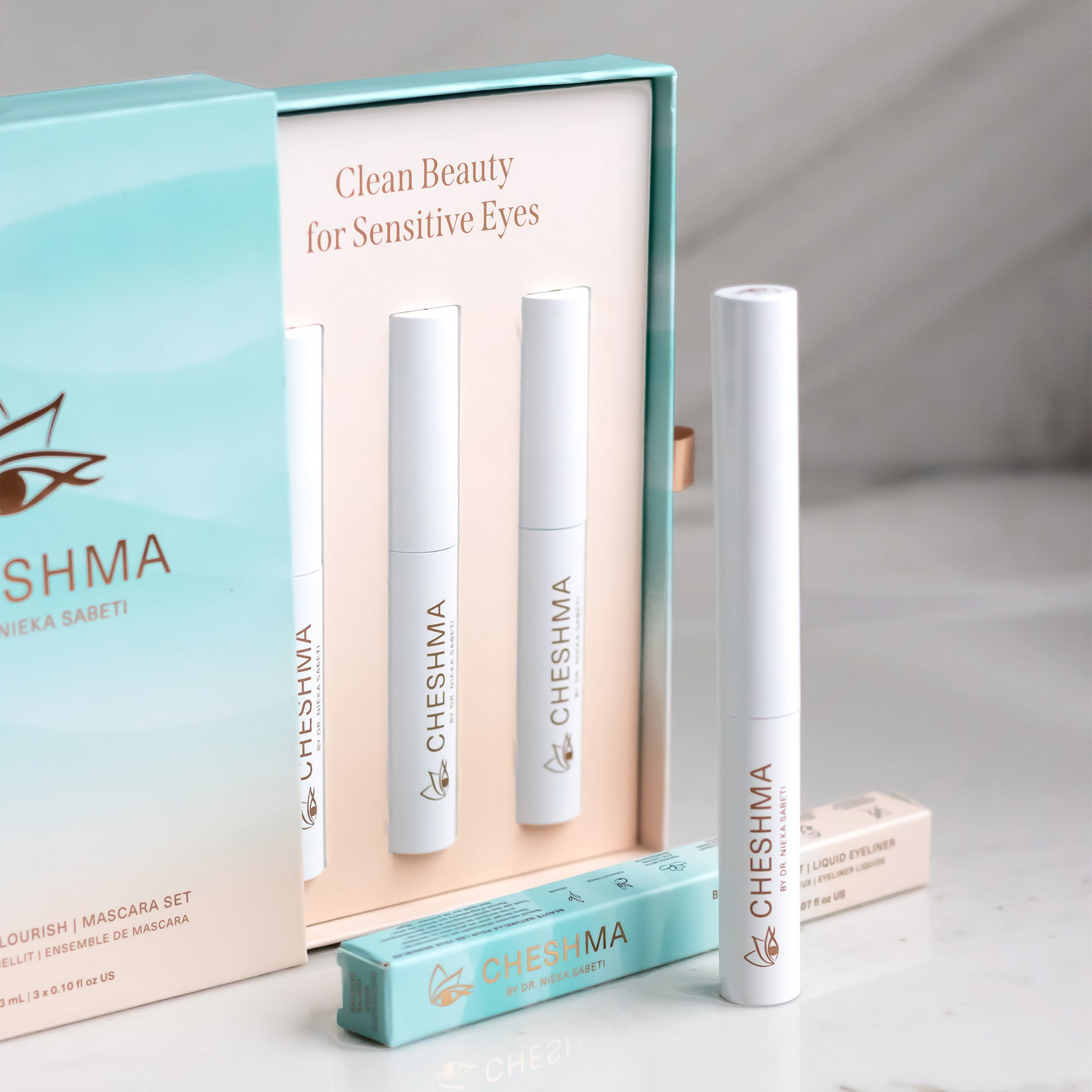teal blue wave box with sand colour inside with mascara white vials and eyeliner on marble countertop of Cheshma brand