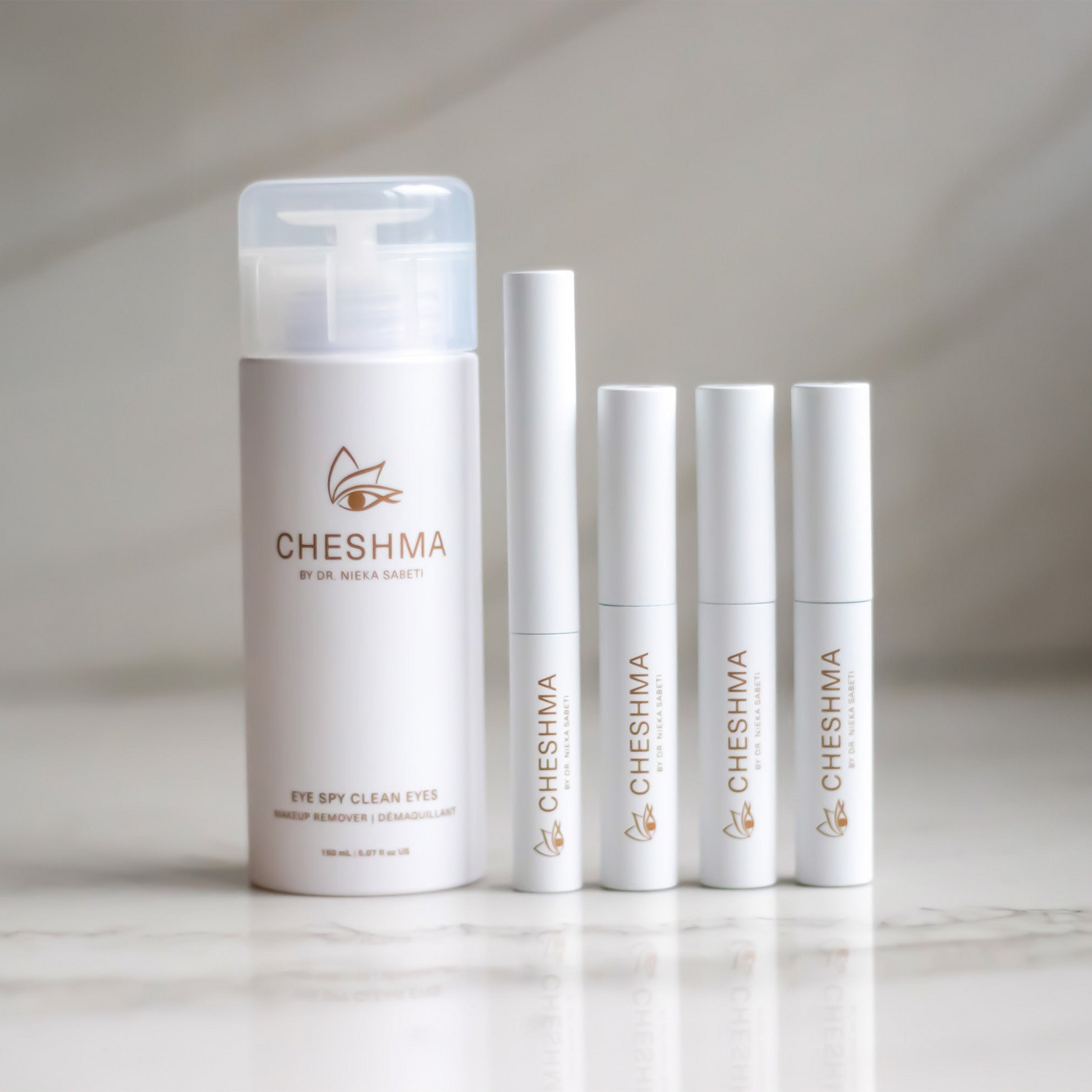 Cheshma makeup remover, eyeliner and 3 mascaras in white vials on marble counter