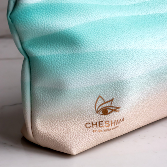 Gradient pouch with 'Cheshma' branding on a marble surface